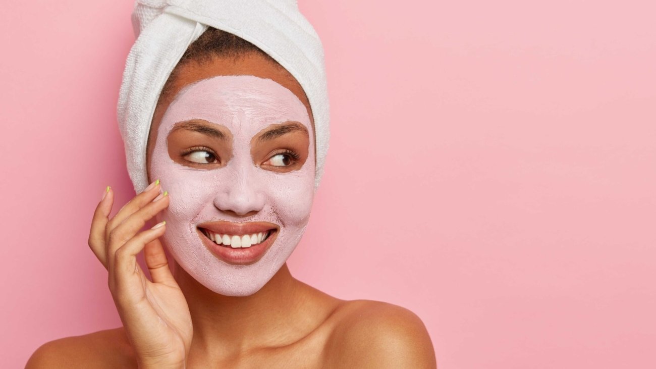 lovely-woman-has-delicate-sooth-skin-wears-cream-mask-face-reduce-acnes-has-healthy-complexion-hygienic-treatments-wears-white-wrapped-towel-head (1)